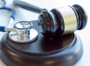 A wooden gavel and stethoscope rest on a sounding block.